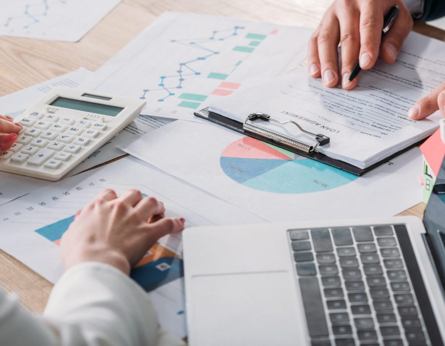 partial view of man studying loan agreement and businesswoman using calculator while sitting at