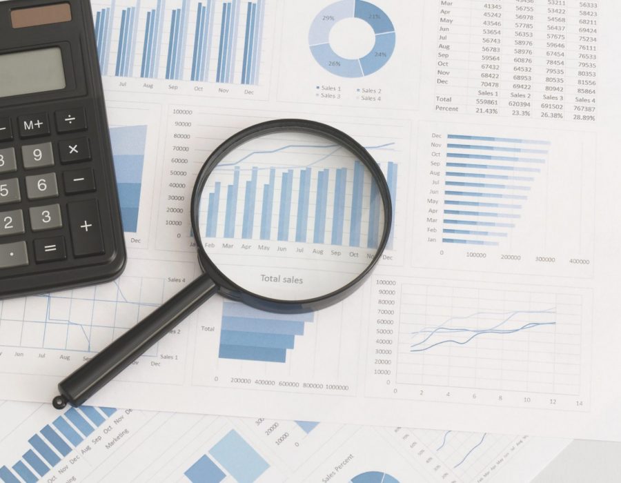 Business graphs, charts, magnifying glass and calculator on table. Financial development